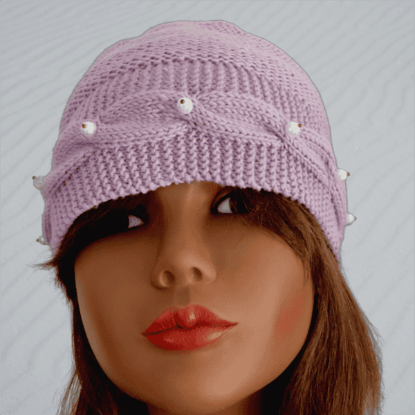 Tricot fait main - Un bonnet en laine lilas avec une bordure torsadée et des perles blanches sur le devant et deux perles sur l'arrière