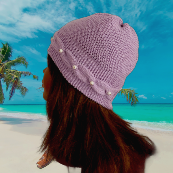 Tricot fait main - Un bonnet en laine lilas avec une bordure torsadée et des perles blanches sur le devant et sur deux perles sur l'arrière