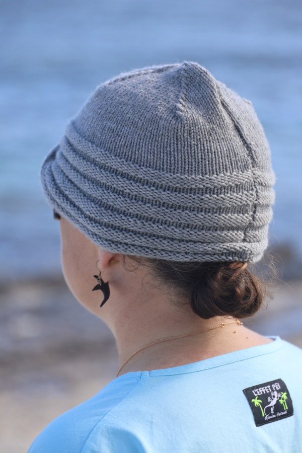 Un bonnet tricoté main en mérinos extrafine gris, orné d’une broche en strass pour une touche de glamour
