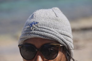Un bonnet tricoté main en mérinos extrafine gris, orné d’une broche en strass pour une touche de glamour