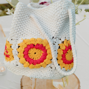 “Sac à main granny éco chic en coton recyclé avec motifs de tournesol rouge et blanc cassé sur une table décorée.”