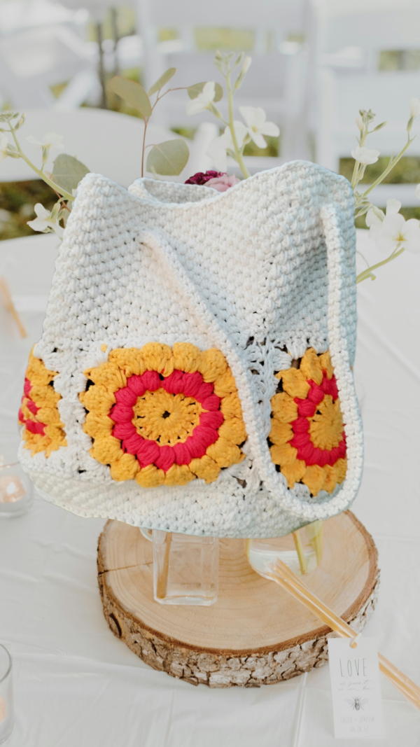 “Sac à main granny éco chic en coton recyclé avec motifs de tournesol rouge et blanc cassé sur une table décorée.”