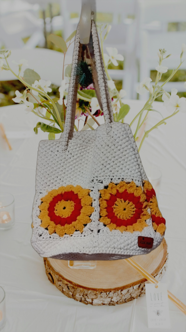 “Sac à main granny éco chic en coton recyclé avec motifs de tournesol rouge et blanc cassé sur une table décorée.”