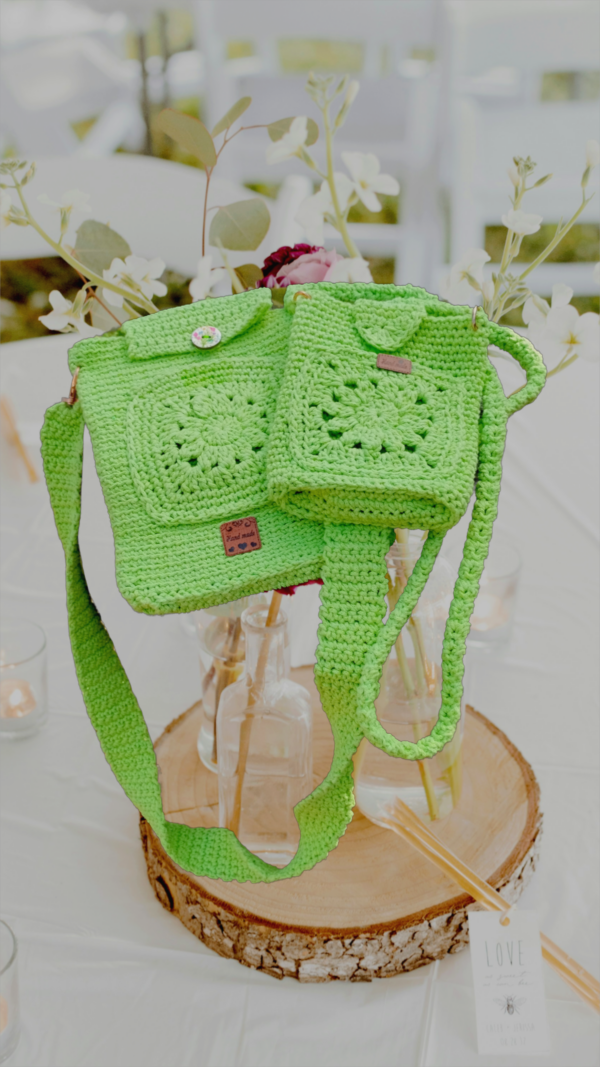 “Pochette téléphone et porte-cartes crochetée en coton recyclé de couleur anis, avec motifs granny, mailles serrées et mailles coulées. Lanière généreuse pour plus de confort.”