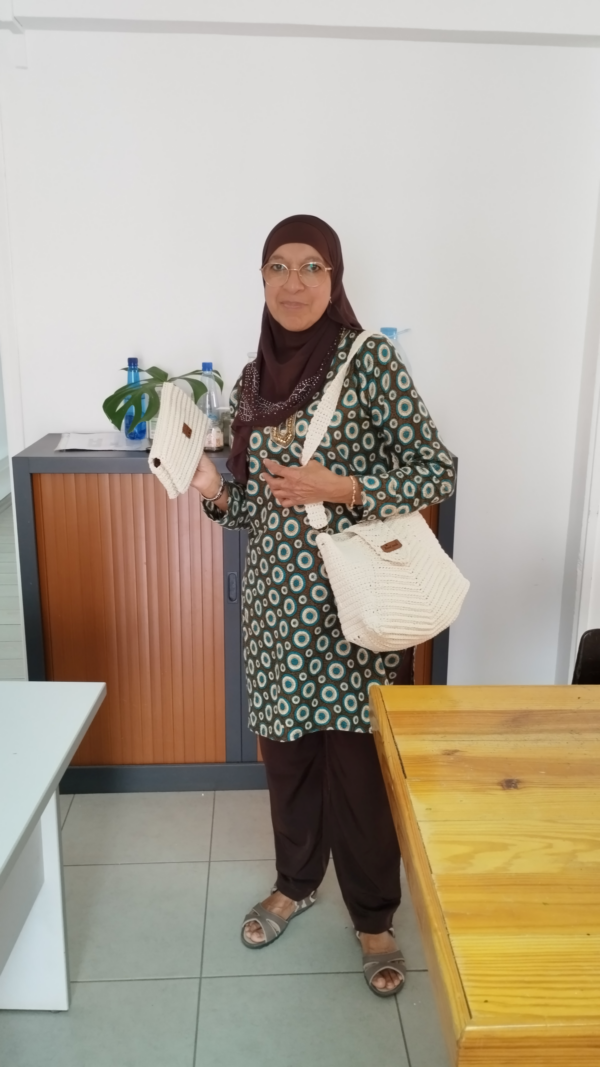 Un sac à rabat élégant et une pochette en coton recyclé, fait main avec des motifs délicats de couleur blanc cassé. Accessoires portés par une femme élégante