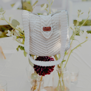 Un sac à rabat élégant en coton recyclé, fait main avec des motifs délicats de couleur blanc cassé.