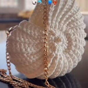 Sac crocheté à la main en coton recyclé, forme inspirée des coquillages, avec une chaîne en métal et une perle nacrée en ornement.